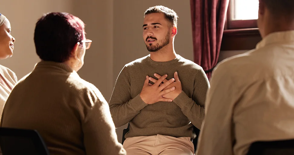 build bridges across divides Young man speaks sincerely in a group discussion, hands placed over his heart