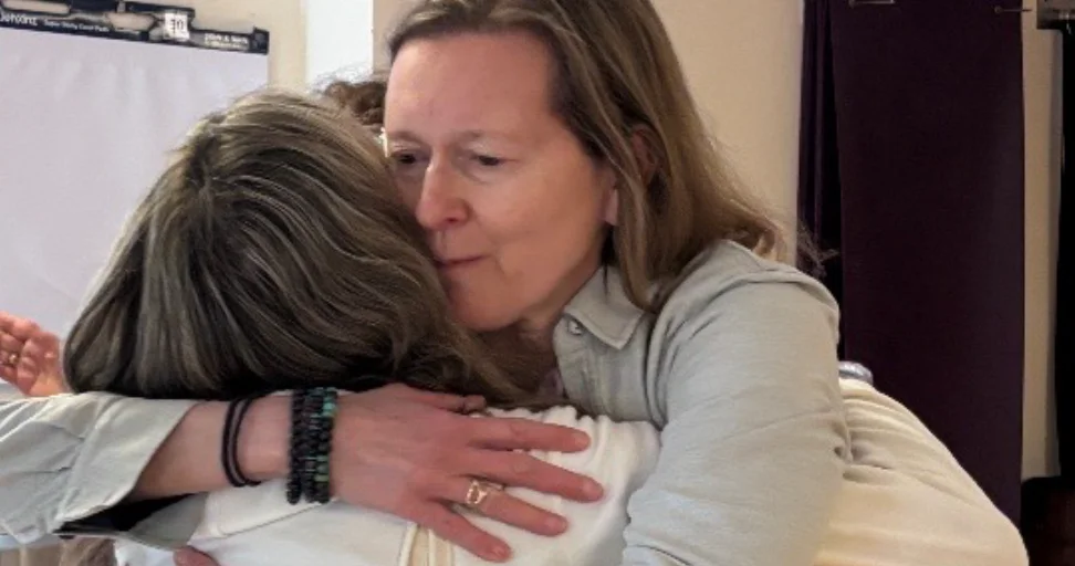 foster healing resilience Two women sharing a warm, heartfelt embrace in an indoor setting.