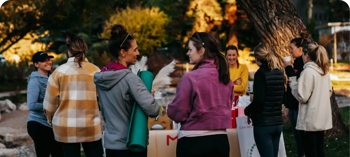 A group of women chatting and relaxing together at an outdoor wellness event.