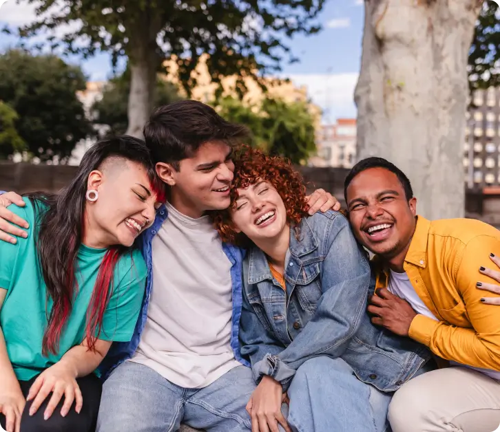 dia 1 1x Four diverse young friends laughing together outdoors in a city park