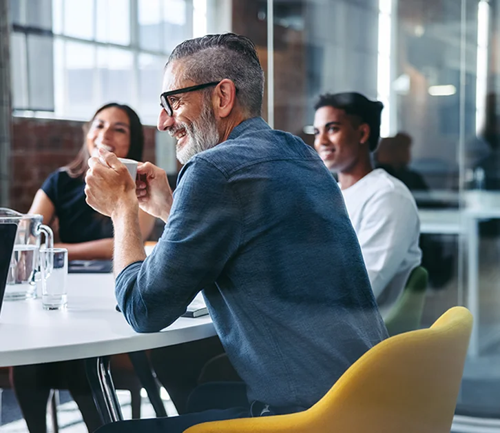 Colleagues laughing and chatting during a relaxed office meeting