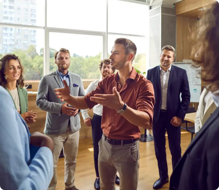 Facilitator leading a group discussion with colleagues standing in a circle in a modern office