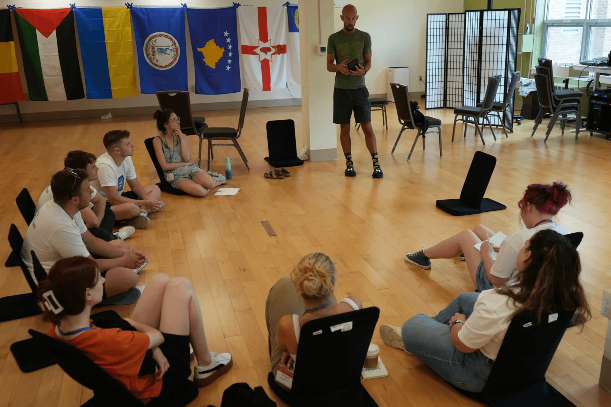 A group of young adults sitting in a circle on the floor during an interactive workshop session.