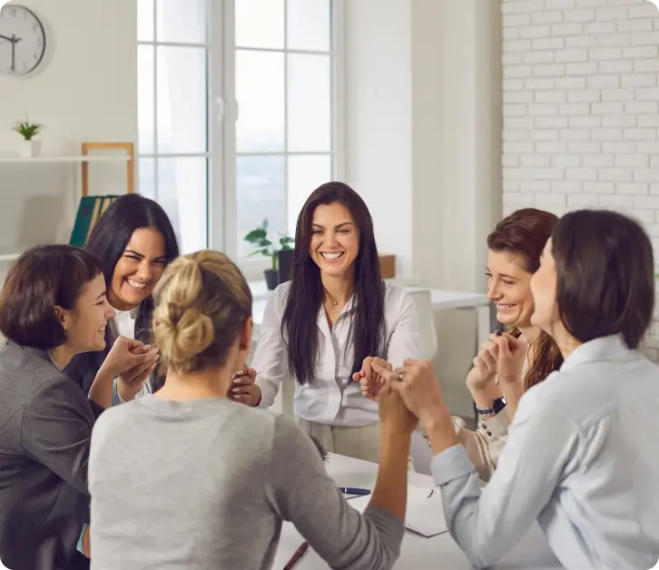 Group of women smiling and laughing together during a collaborative office meeting