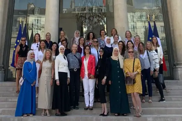 Group of women posing on steps of an official French government building with EU and French flags